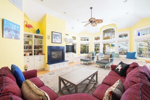 A living room with a fireplace, seating area, and large windows. - Soundfront w/ Hot Tub, Game Room & Resort Perks! (Corolla)