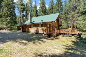A log cabin with a green metal roof, wooden deck, and a chimney. - Tranquil 3-bedroom cabin in charming Darby perfect for relaxing stays (Darby)