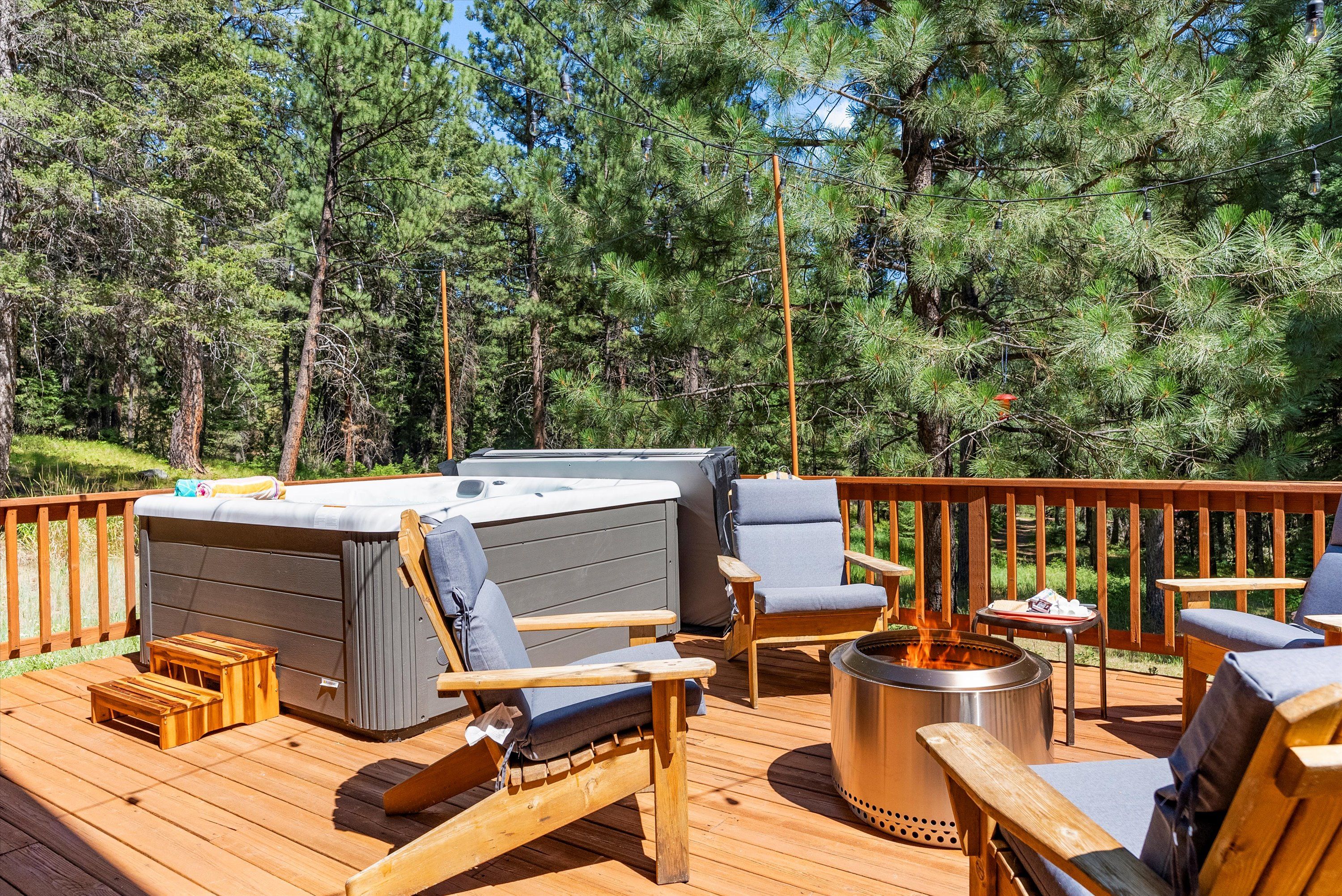 A deck with a hot tub, seating, and a fire pit.