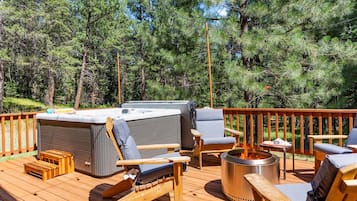 A deck with a hot tub, seating, and a fire pit.