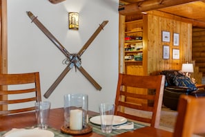 A wooden interior with a dining table set for two, a candle centerpiece, and a wall-mounted crossbow. - Tranquil 3-bedroom cabin in charming Darby perfect for relaxing stays (Darby)