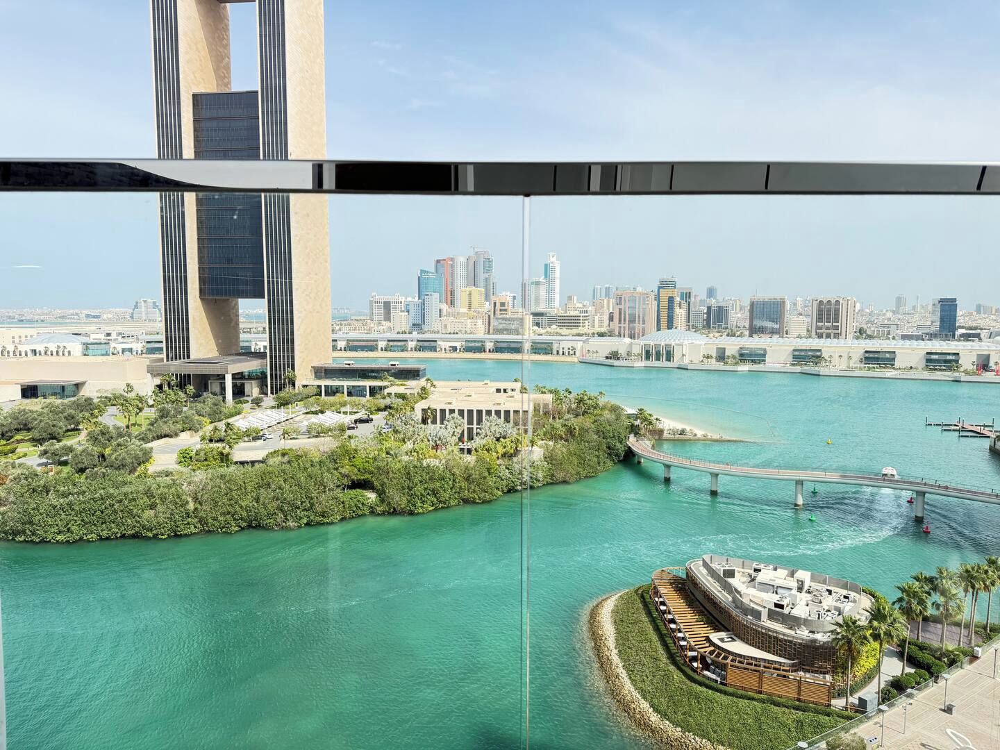 Een pand aan het water met een rond gebouw, een brug en een stadsachtergrond.