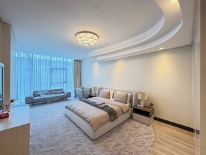 A modern bedroom with a large bed, a sofa, a bedside table, and a chandelier. - Stunning Four Seasons Views by Flouri FBB913O (Manama)