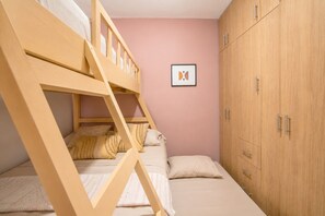 Ein Etagenbett mit Holzleiter, ein Schrank mit mehreren Türen und ein gerahmtes Bild an der Wand.