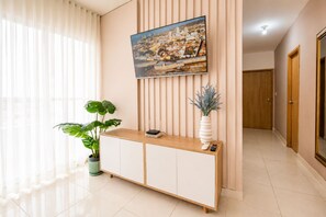 A hotel reception area with a wooden console table, a potted plant, a vase with blue foliage, and a framed cityscape picture on the wall. - Group Vacation • Ocean View • Swimming Pool (Cartagena)