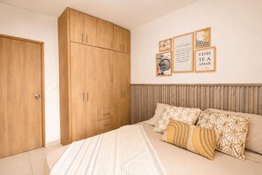 A bedroom with a bed, a wardrobe, and wall art. - Group Vacation • Ocean View • Swimming Pool (Cartagena)