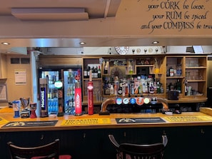Eine Bar mit einer Auswahl an Spirituosenflaschen und einem Schild mit der Aufschrift 'The Akston The Original Mechanical Craft Brewer'.