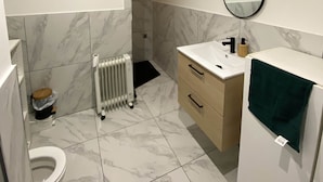 Casa de banho moderna com sanita, lavatório, espelho e radiador.