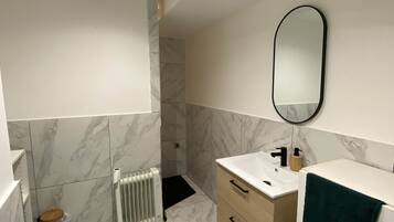 Een moderne badkamer met toilet, wastafel, spiegel en radiator.