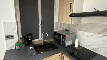 Een kleine keuken met een spoelbak, een magnetron en een koffiezetapparaat.