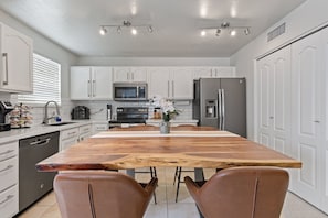 A modern kitchen with white cabinets, stainless steel appliances, a wooden island, and leather chairs. - Min 2 Mayo Clinic, St. Joseph's Hospital, Chase Stadium, Desert Botanical Garden (Phoenix)