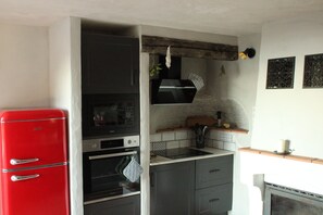 Eine kleine Küche mit einem roten Kühlschrank, einem eingebauten Backofen, einer Mikrowelle und einem Spülbecken.