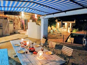 Ein Essbereich im Freien mit Tisch und Stühlen, umgeben von einer überdachten Terrasse.