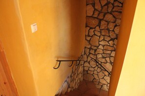 Ein schmaler Korridor mit einer Steinwand und einer Holztür.