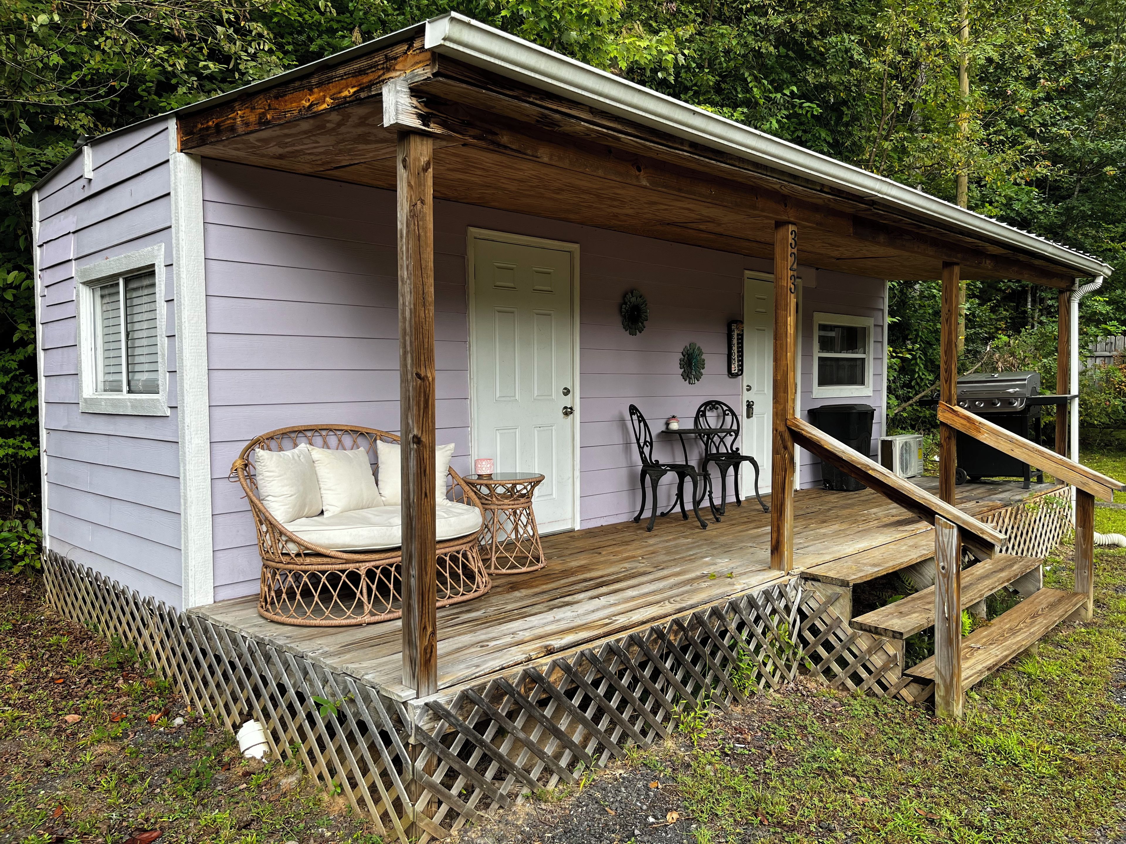 A wooden porch with a covered seating area, a grill, and a door leading to the interior.