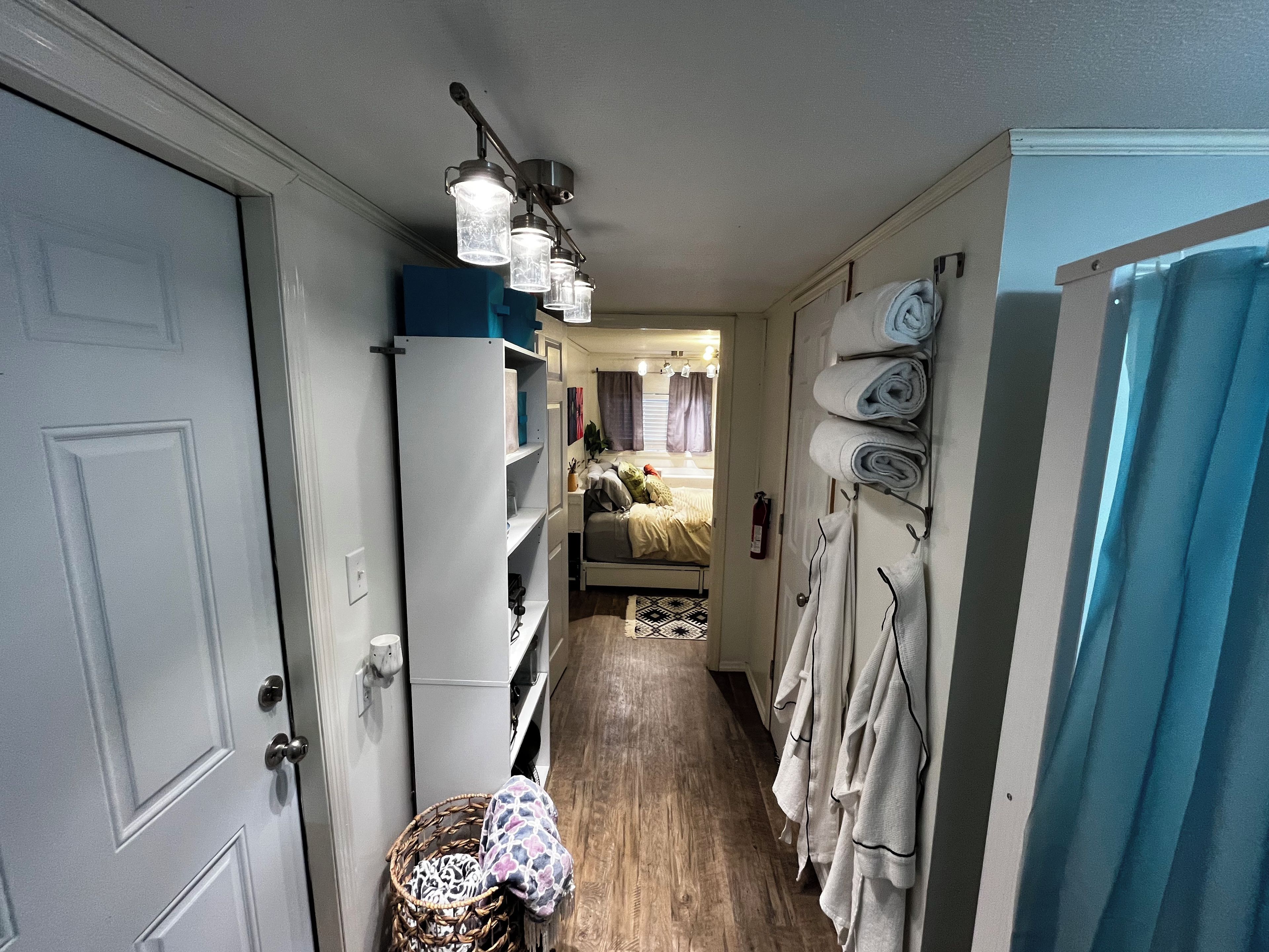 A narrow hallway with a bed, a wardrobe, and a hanging light fixture.