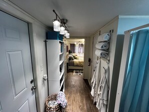 A narrow hallway with a bed, a wardrobe, and a hanging light fixture. - Lovely 1-bedroom mobile home with AC in peaceful Cherokee (Cherokee)