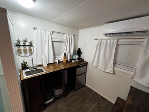 A compact kitchenette with a sink, a microwave, and a small refrigerator. - Lovely 1-bedroom mobile home with AC in peaceful Cherokee (Cherokee)