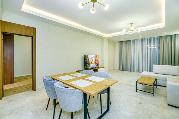 Una sala de estar moderna con comedor, televisión y sofá.
