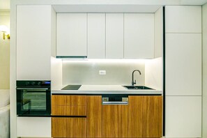 Una cocina compacta con horno integrado, lavamanos y armarios de madera.