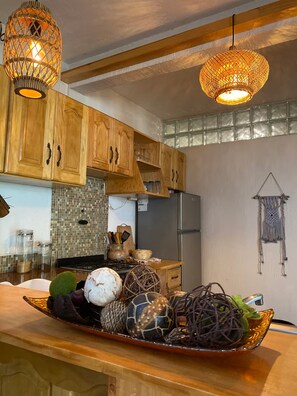 A kitchen with wooden cabinets, a refrigerator, and a decorative tray with various items on the counter. - Casa Bentley: 360° rooftop terrace + lush garden (San Pedro La Laguna)