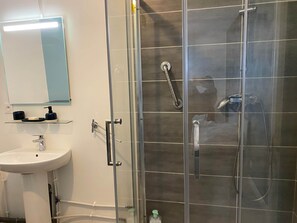 Een moderne badkamer met een douchecabine van glas, een wit wastafelmeubel en een spiegel erboven.