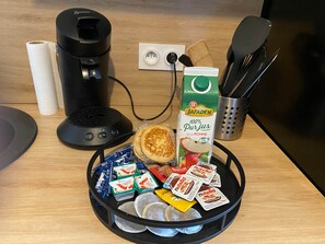 Een keukentrap met een koffiezetapparaat, een pak Jafaden-sap, een spatel, een messenblok en een schaal met etenswaren, waaronder Nutella en koekjes.