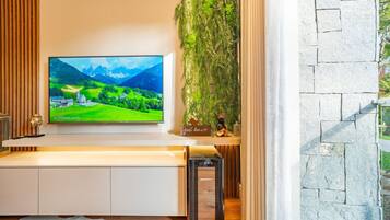 Ein modernes Wohnzimmer mit einem an der Wand befestigten Flachbildfernseher, einer kleinen Statue und einer Zierpflanze.