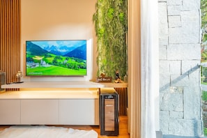 A modern living room with a flat-screen TV mounted on a wall, a small statue, and a decorative plant. - Vêneto Vicenza 103 (Gramado)