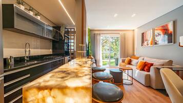 A modern kitchen with a marble countertop and a dining area with a sofa and stools.