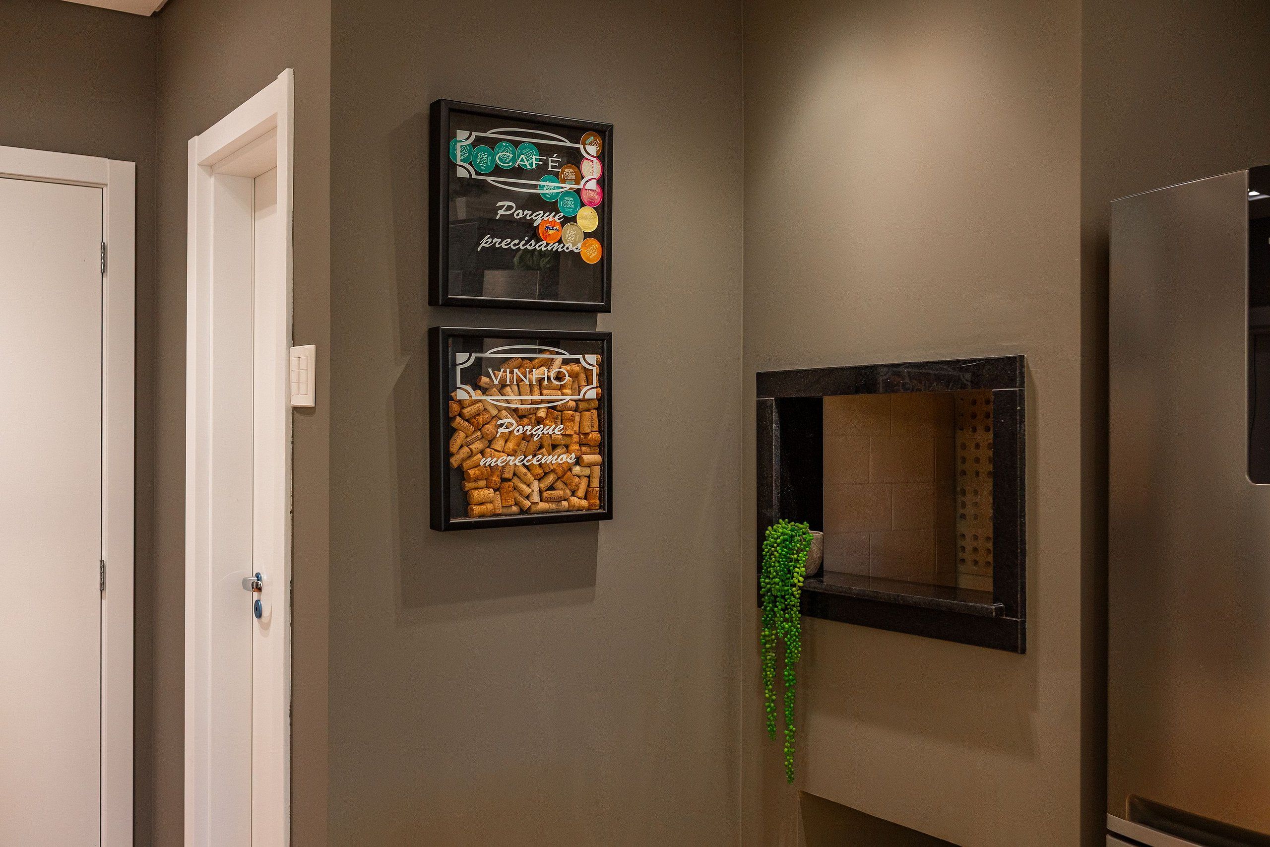 A hallway with a door, two framed pictures, and a potted plant.
