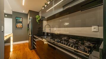 Una cocina moderna con un refrigerador de acero inoxidable, una estufa a gas y una encimera negra.