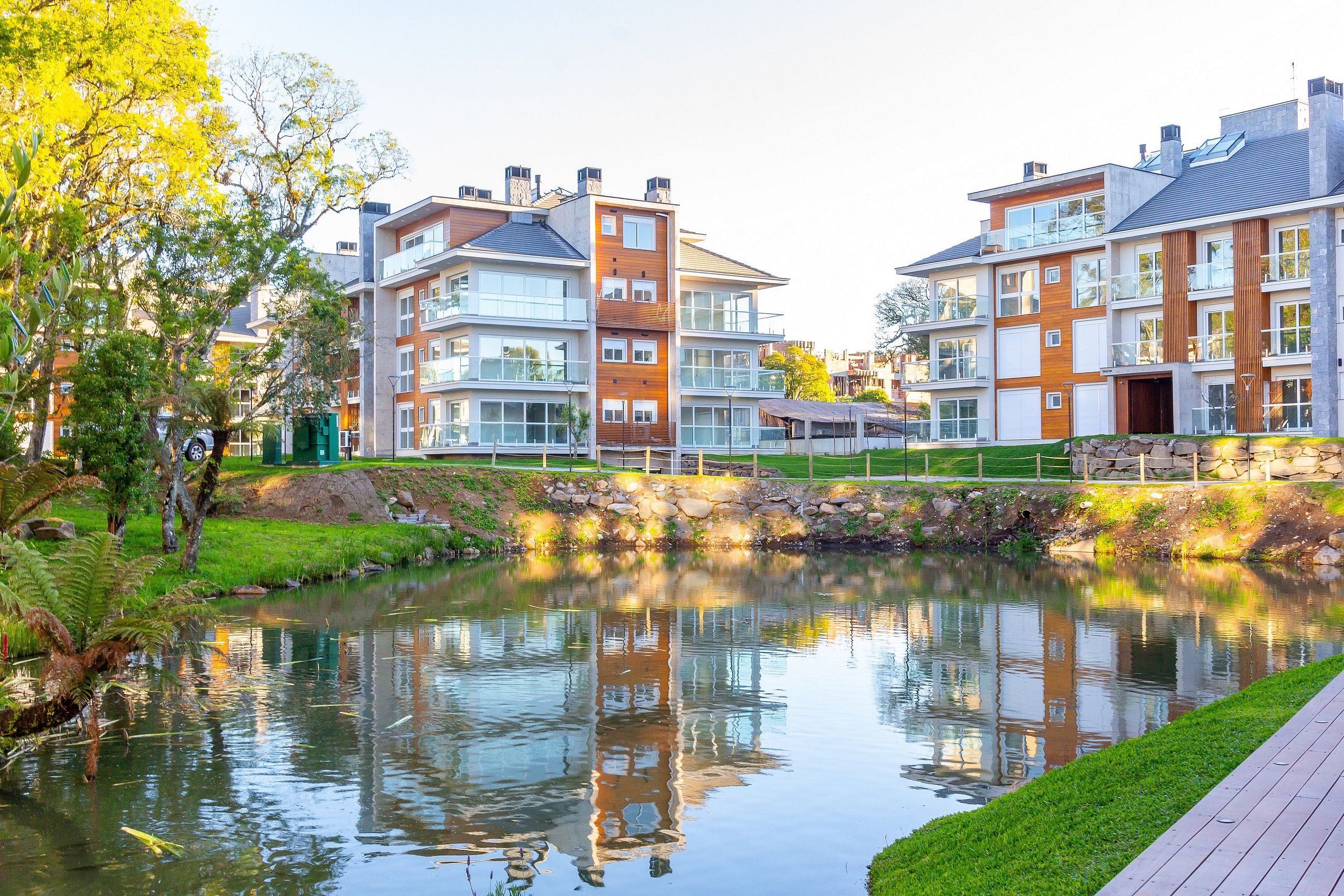A modern apartment building with multiple floors, large windows, and a small water feature in front.
