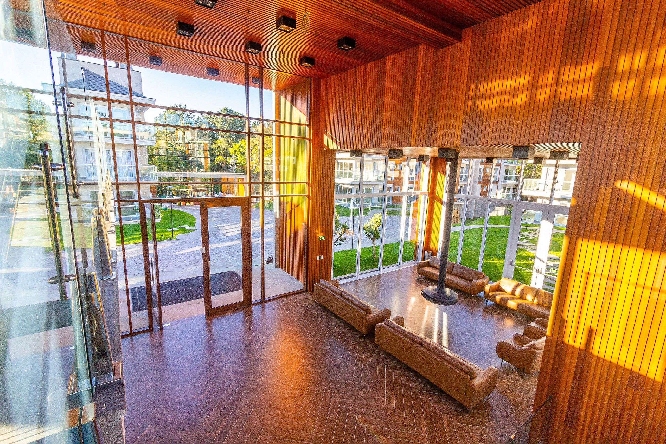 A modern lobby with glass doors, a herringbone floor, and a seating area with sofas.