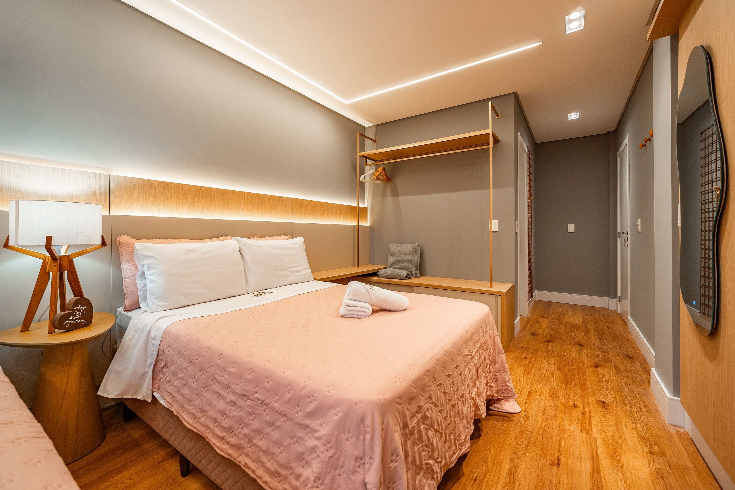 A modern bedroom with a bed, bedside table, and a hanging light fixture.