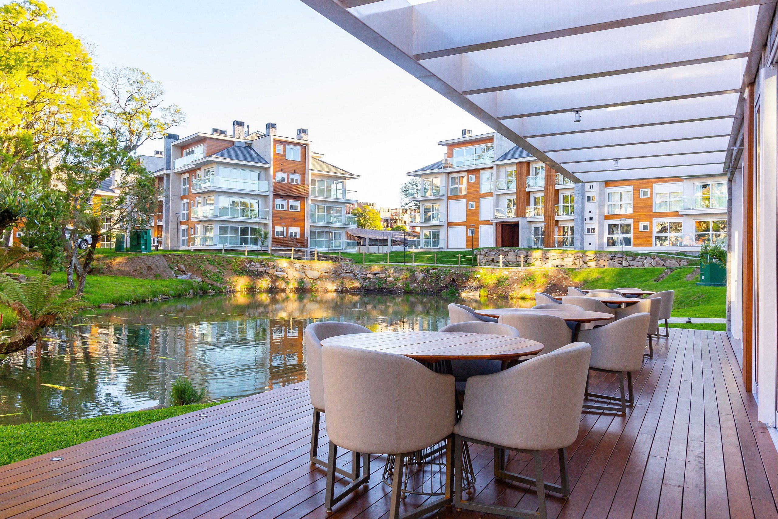 A deck with outdoor seating overlooking a pond and residential buildings.