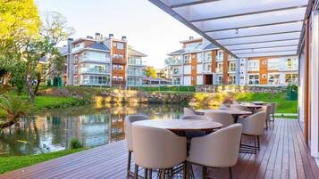 A deck with outdoor seating overlooking a pond and residential buildings.