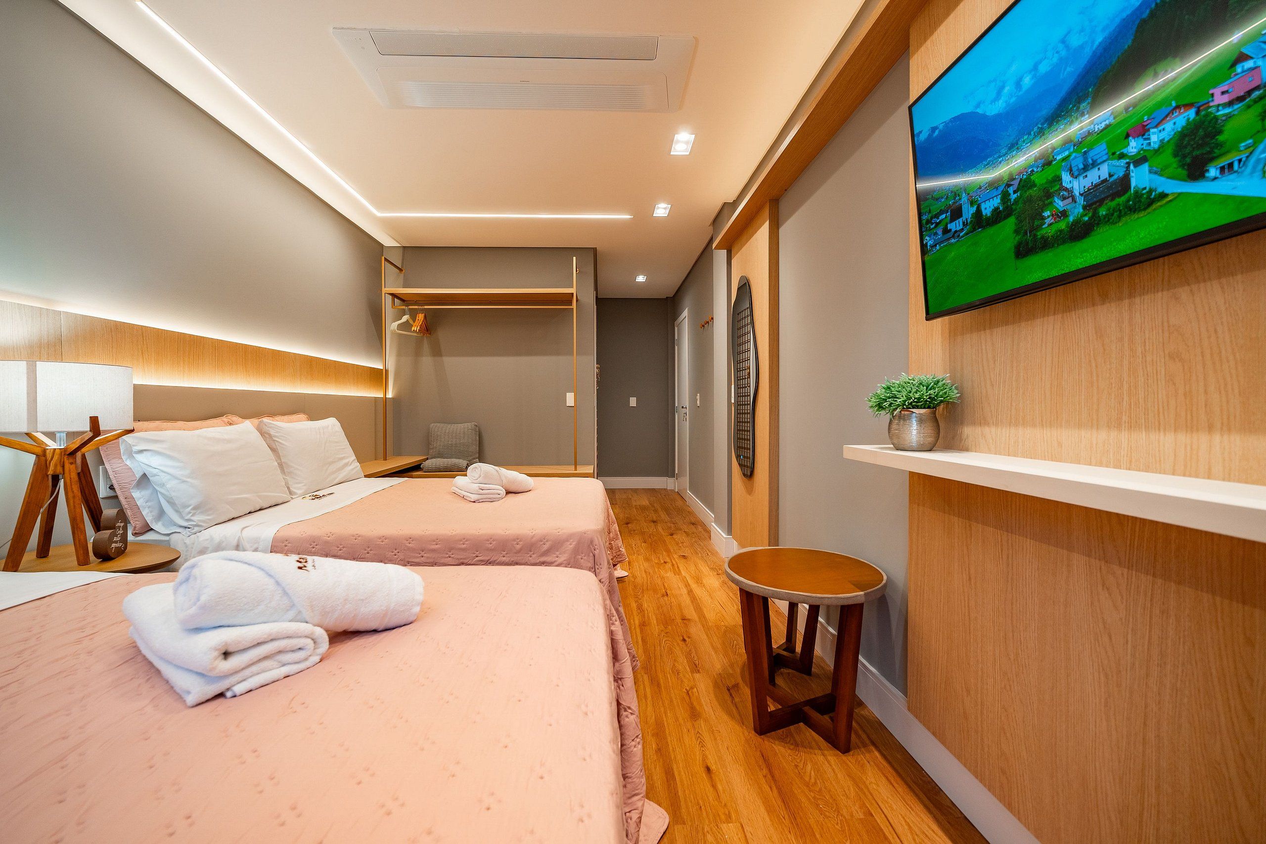 Ein Hotelzimmer mit einem Bett, einem Fernseher, einem kleinen Tisch und einem Regal mit einer Pflanze.