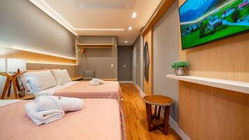 Ein Hotelzimmer mit einem Bett, einem Fernseher, einem kleinen Tisch und einem Regal mit einer Pflanze.