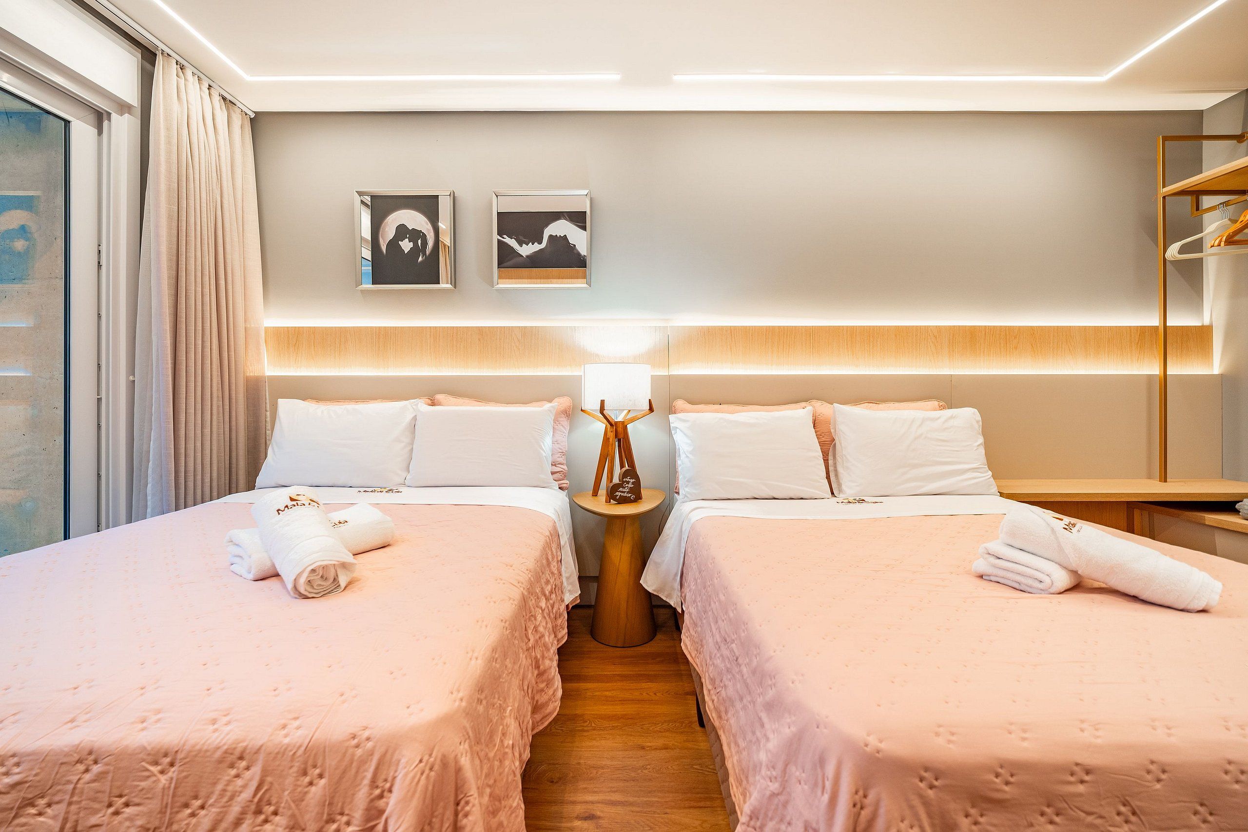 Habitación de hotel con dos camas, una mesita de noche, una lámpara y una obra de arte en la pared.