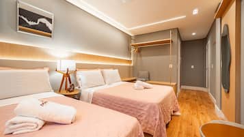 A hotel room with two beds, a bedside table with a lamp, a mirror, and a wardrobe.