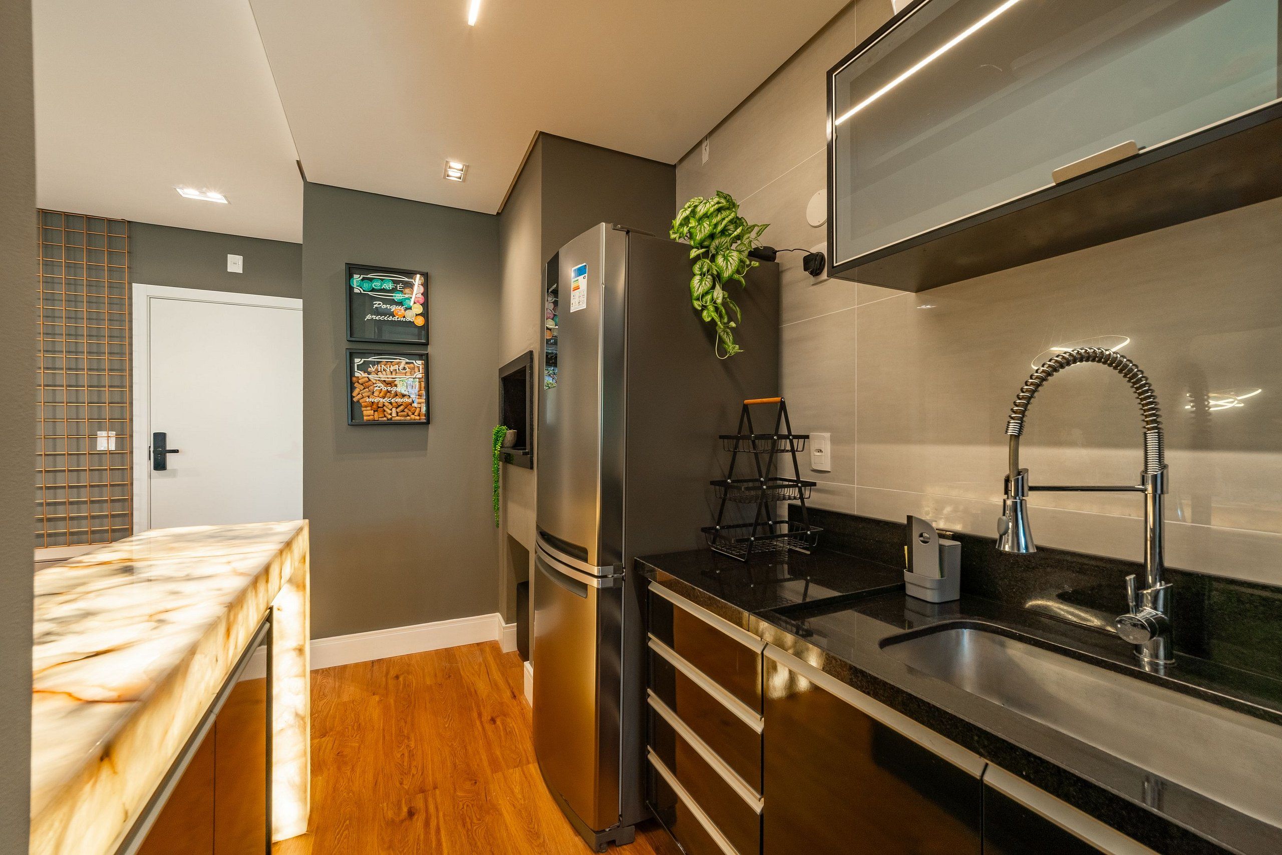 Una cocina moderna con un refrigerador de acero inoxidable, una encimera negra y un lavamanos con grifo moderno.