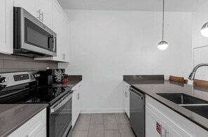 A kitchen with white cabinets, a black stove, a microwave, and a dishwasher. - 5BR house with private pool in Storey Lake (Kissimmee)