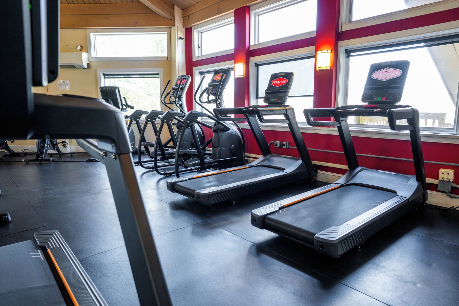 Un gimnasio con cintas de correr y equipo de ejercicio.