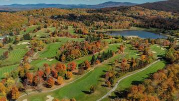 A golf course with multiple fairways, sand traps, and a lake.