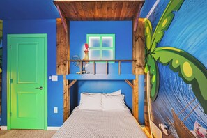 Een kamer met een bed, een groene deur, een raam en een muurschildering van een zeegezicht.
