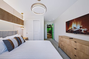 Ein modernes Schlafzimmer mit einem großen Bett, einer hölzernen Kommode und einem Gemälde eines Kamins.
