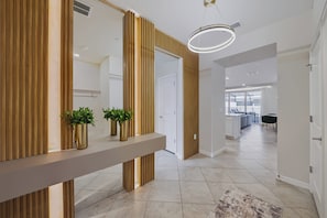 Ein modernes Interieur mit einer Holzwand, einem Flur, der zu einem Essbereich führt, und einer sichtbaren Küche.