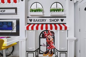Uma padaria com um letreiro do Mickey Mouse, um monitor de computador e uma bicicleta ao fundo.