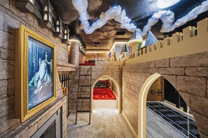 A themed room with stone walls, a framed picture, a ladder, a red carpet, and a castle-like structure. - 7BR house with private pool in clermont (Clermont)